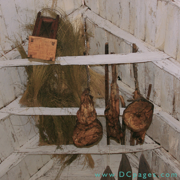 flax, hams, and clothing are hung on the farm house ceiling beams.