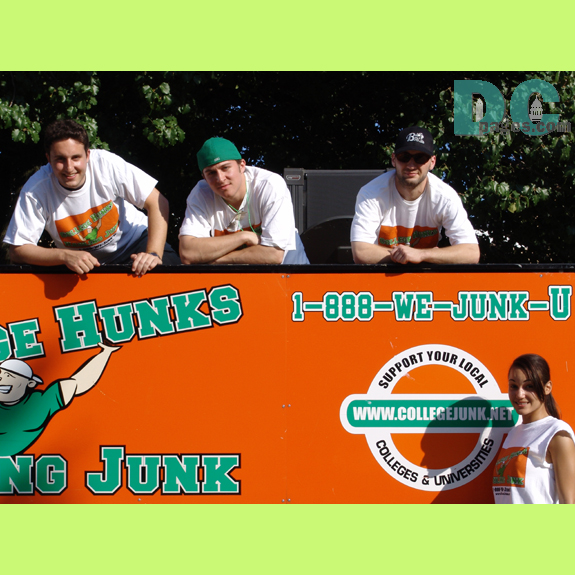Three guys hang over their sign 1-800-WE-JUNK-U
