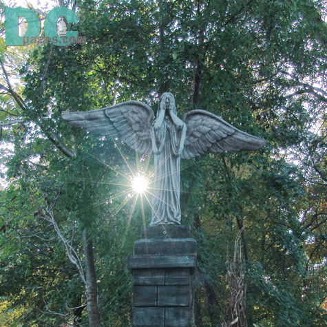 An angel covers its face knowing the darkness will soon cover this park.