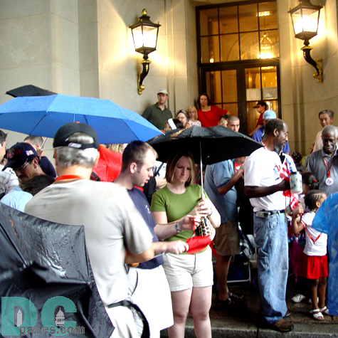 A man shows a woman a Fourth of July souvenir lanyard he just acquired.