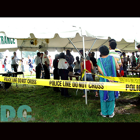 Inside a security search tent, people have their bags checked.