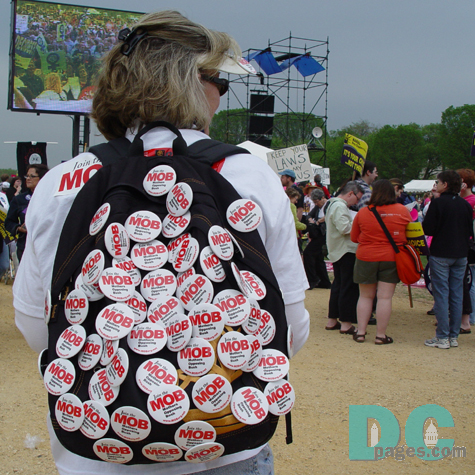 Female demonstrator with MOB (Mothers Opposing Bush) pinned to her daypack.