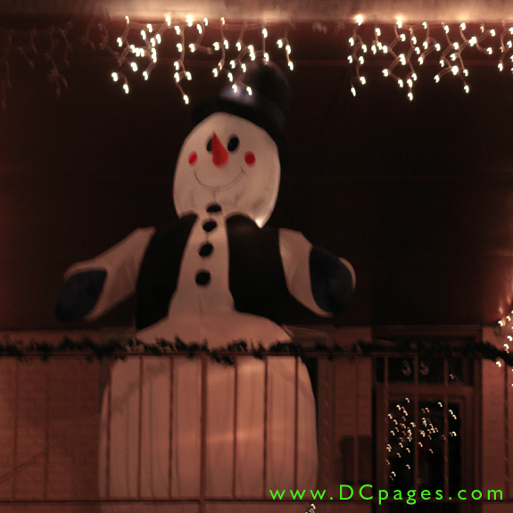 A giant inflatable snowman wearing a top hat, vest, and mittens are on display.