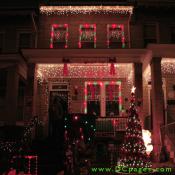"A Happy Holiday's" sign with red ribbons on each side showcases a house filled with many outdoor decorations.