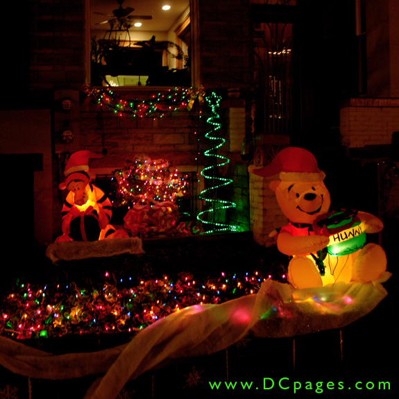 An inflatable Winnie the Pooh and Tigger are surrounded by a green spiral tree, and many multicolored lights.