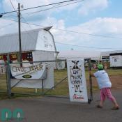 Parking lot view of the entrance gates to the Prince William County Fair. Sign left - CIVAL WAR ENCAMPMENT. Sign right - Advertisement - EAT MORE CHICKEN