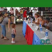 A curly redhaired little girl stands in front of three judges.