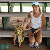 A little girl in a sun dress hugs her mother.