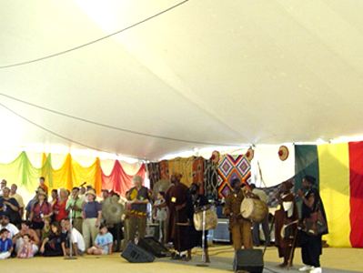 The musicians play as the crowd gazes at the masked Dogon dancers. The crowd roared as this dancer on stilts entered the tent from outisde