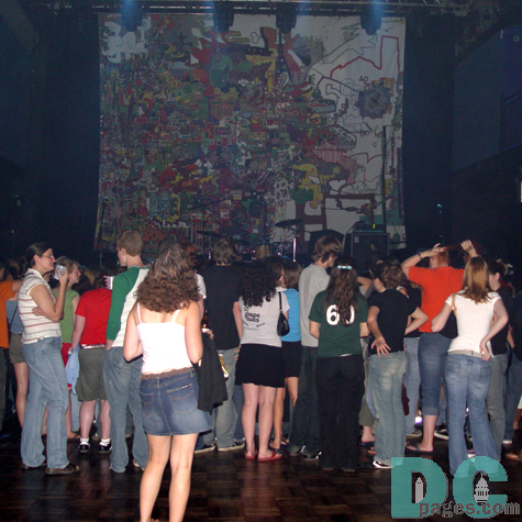 A girl looks at the colorful backdrop, a blow up of Phantom Planet's latest self-titled album cover.