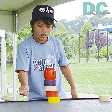 A boy was trying Darumaotoshi. (the daruma block game) 
Several cylindrical blocks are stacked up to form a Bodhidharma doll. The idea is to knock out the blocks with a mallet one by one without toppling the other blocks on top.