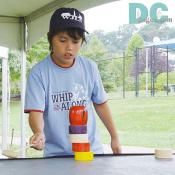 A boy was trying Darumaotoshi. (the daruma block game) 
Several cylindrical blocks are stacked up to form a Bodhidharma doll. The idea is to knock out the blocks with a mallet one by one without toppling the other blocks on top.