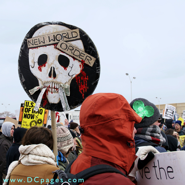 Sign of a bloody skull with dollar bills hanging out of its mouth. On the skull's forehead - NEW WORLD ORDER.