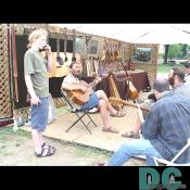 A group of tribesmen take a moment to relax and strum their guitars as one of their son's watches.