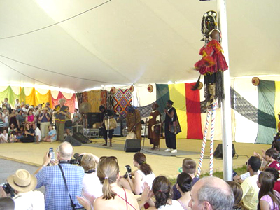 The Dogon dancer on stilts takes a rest, while the band continues to play