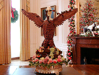 Located in the State Dining room, this eagle made of gold hydrangea leaves stands over a mahogany center table, along with candelabra and urns from the White House vermeil collection