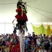 The Dogon dancer on stilts dwarfs over the fellow Dogon dancer, the crowd looks on in awe