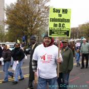 DC resident, Karl Rudder participates in the Voting Rights March. Karl holds up a sign that states, "Say NO to Colonialism in D.C.