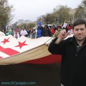 Marchers hold a large flag of the District of Columbia.