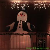 A giant inflatable snowman wearing a top hat, vest, and mittens are on display.
