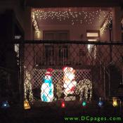A bright snowman and Santa are accompanied by two white reindeer and a string of white lights.